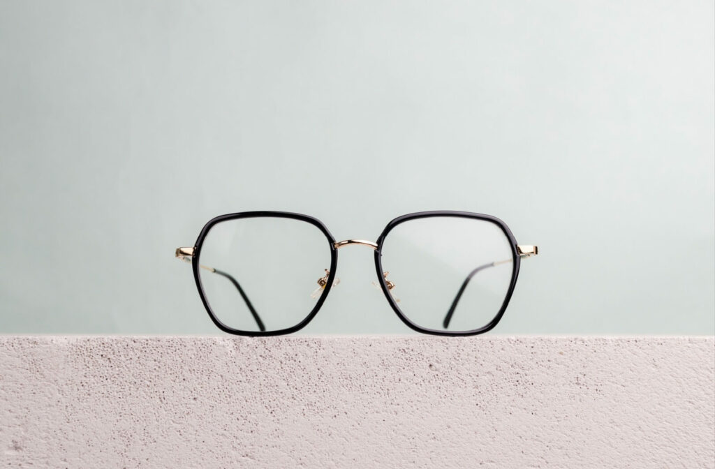 A pair of trendy geometric framed glasses displayed on a cement ledge with a neutral background