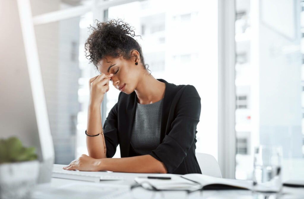 A working professional rubs their tired, dry eyes as they feel a headache coming on.