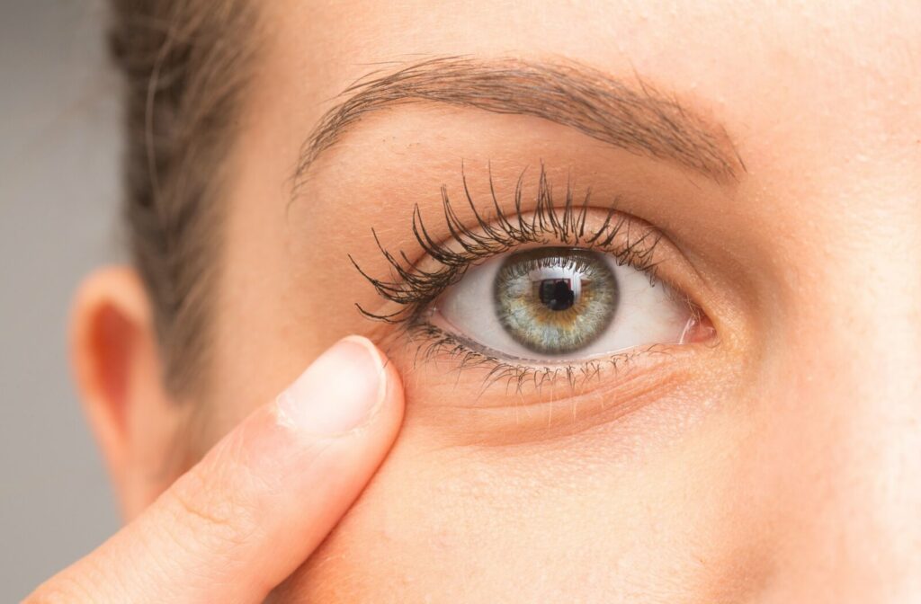 Close-up of a person’s eye with long eyelashes, gently touching the skin beneath the lower eyelid.
