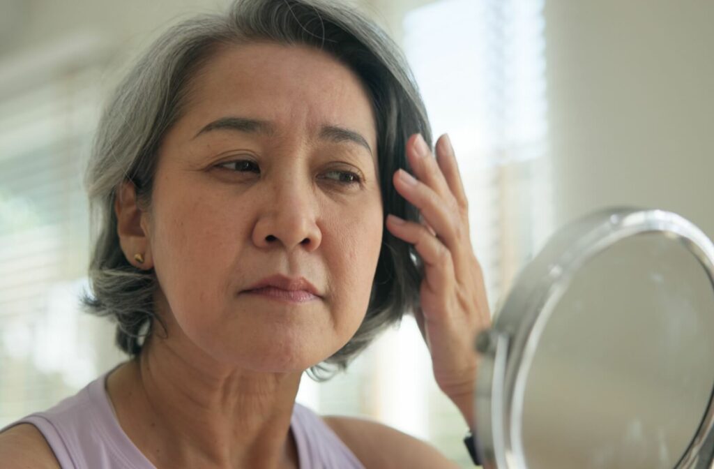An individual looking into a mirror and examining their facial skin for age spots.